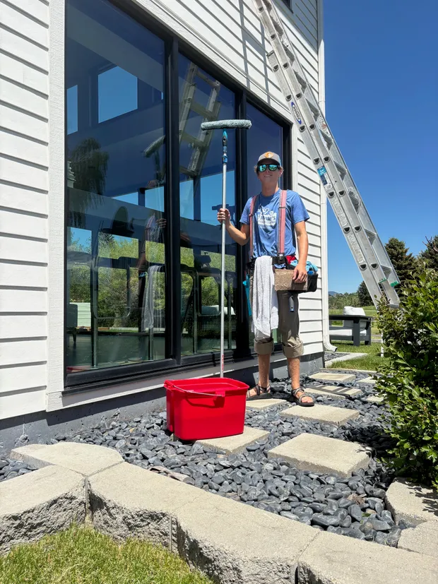 Chase with his ladders, bucket, and scrub pole in front of a wall of clean glass