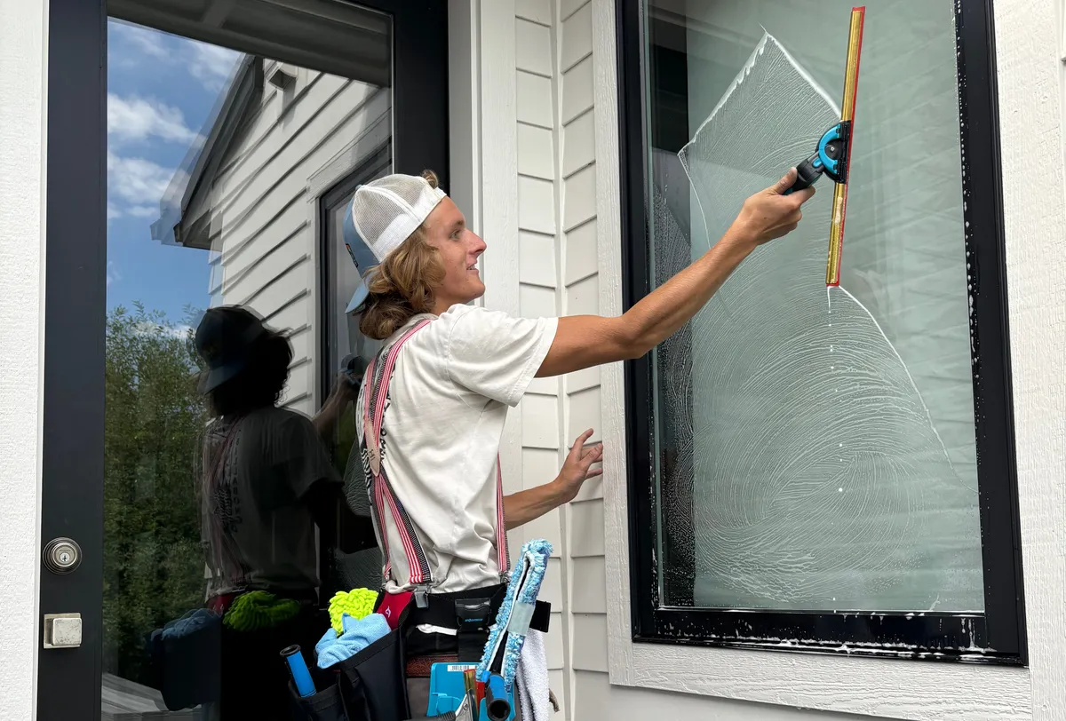 The owner hand-squeegeeing a soapy second-story window