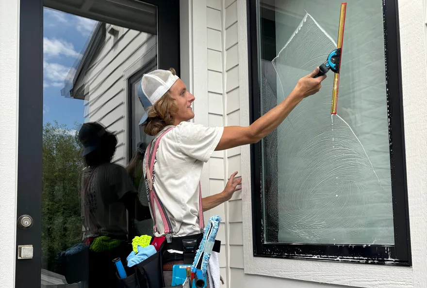 The owner hand-squeegeeing a soapy second-story window