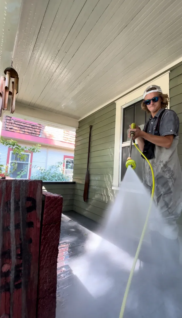 The owner pressure washing a brick porch, the spray fanned across the pavers