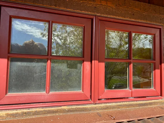 Two panes on the same red window, one still hazy and one cleaned