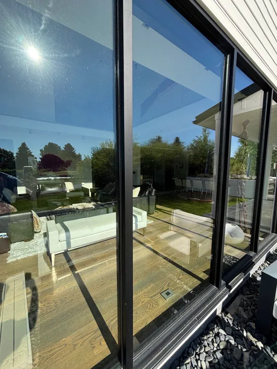 A pristine wall of glass beside patio furniture in full sun