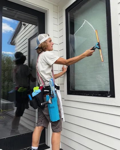 Chase scrubbing a soapy window, tool belt on